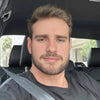 Man sitting in a car wearing a seatbelt, looking at the camera.
