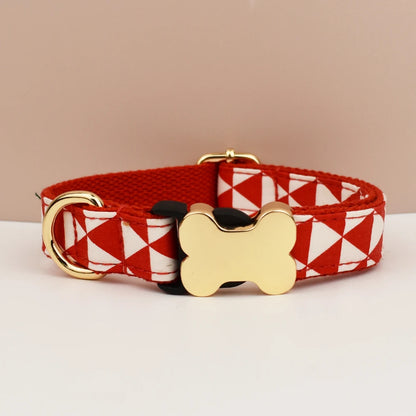 Red and white patterned dog collar with gold bone-shaped tag on a beige background