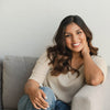 Woman sitting on a couch in a casual setting with a neutral background